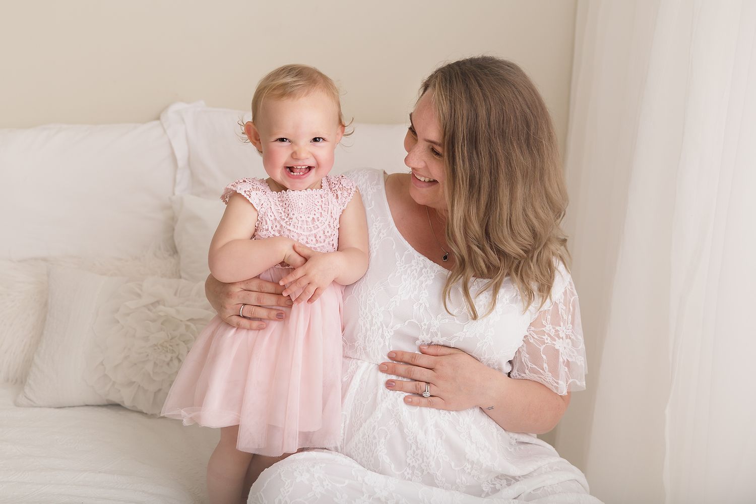 Sweet candid moments captured between a family in white and pink outfits.