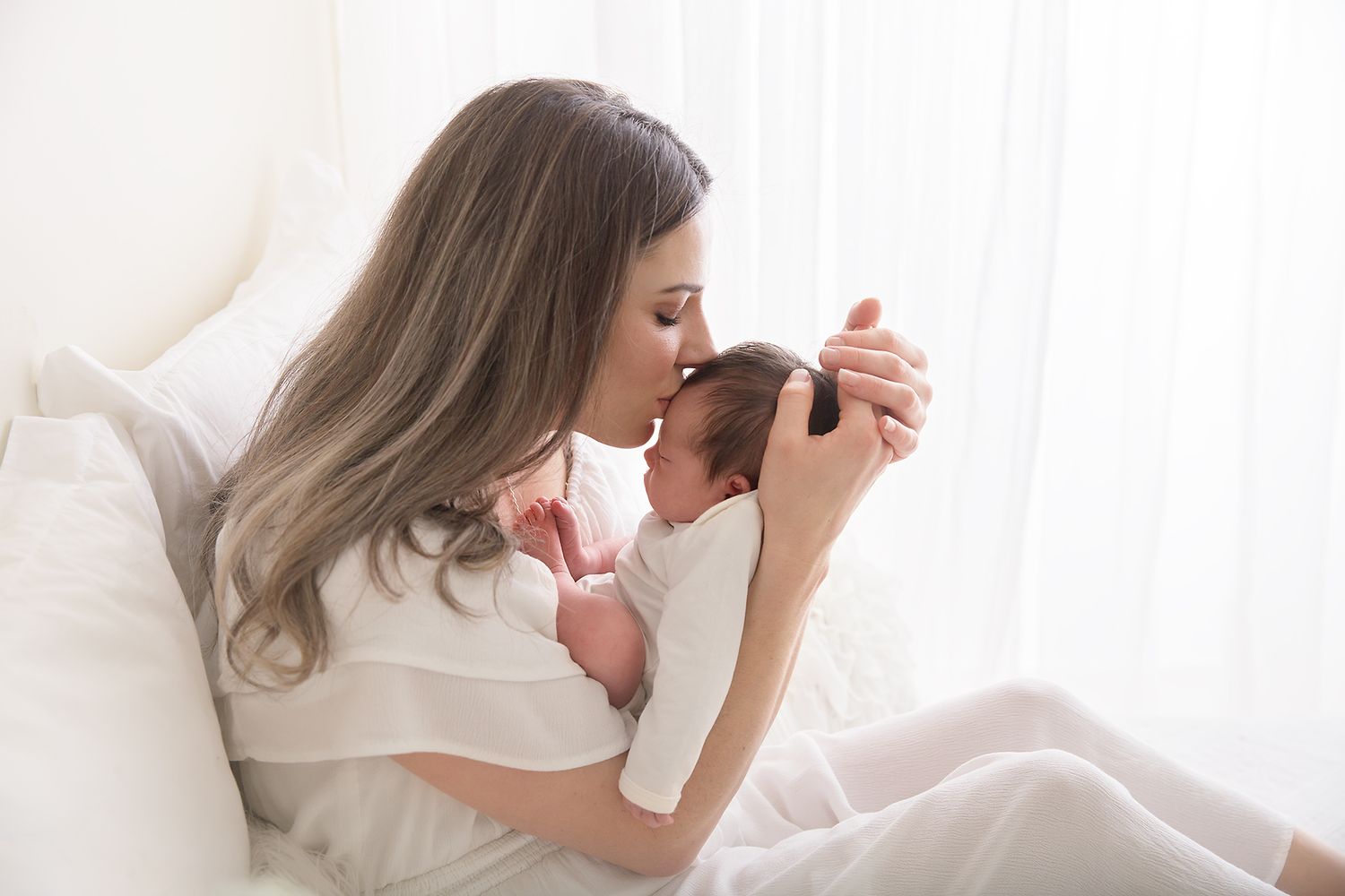 Tender family photography session with white backdrop and soft lighting.