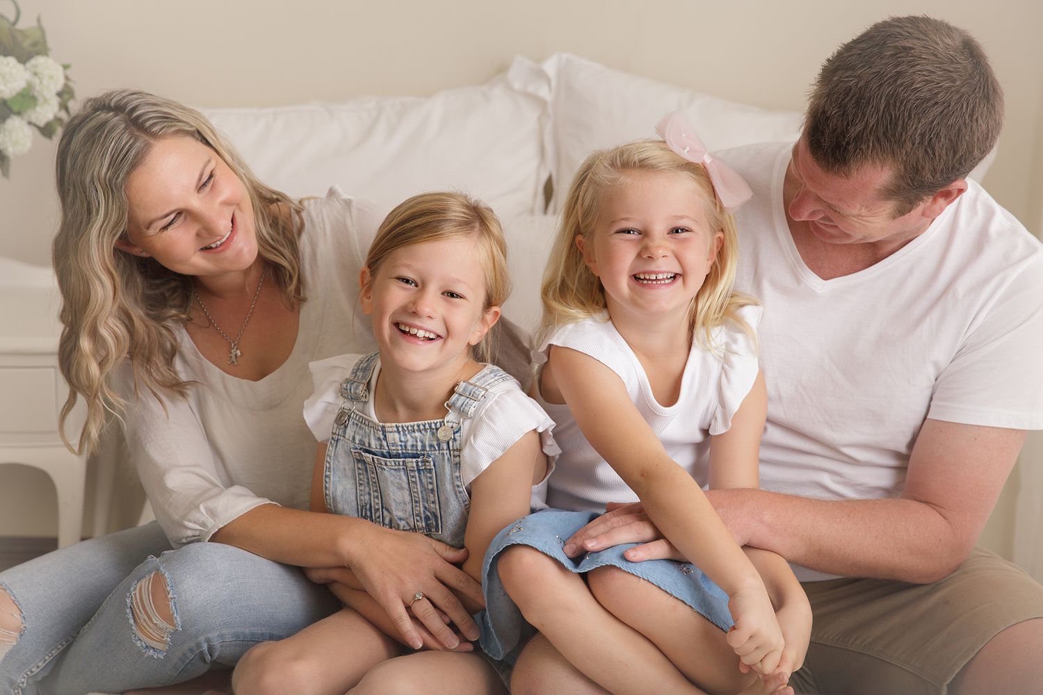 Joyful family moment with parents and children laughing together on light background.