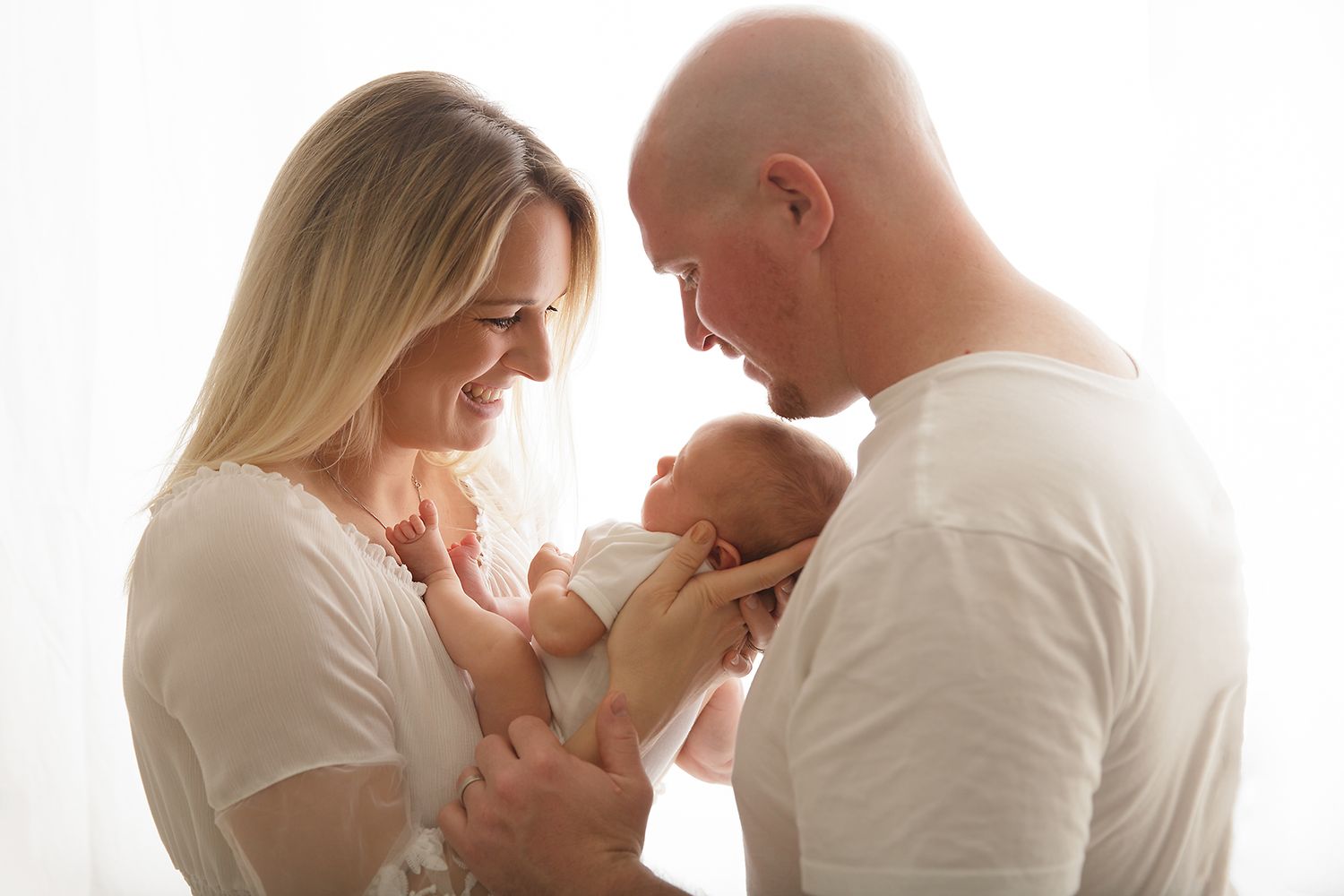 Intimate family portrait session with white backdrop and natural lighting.