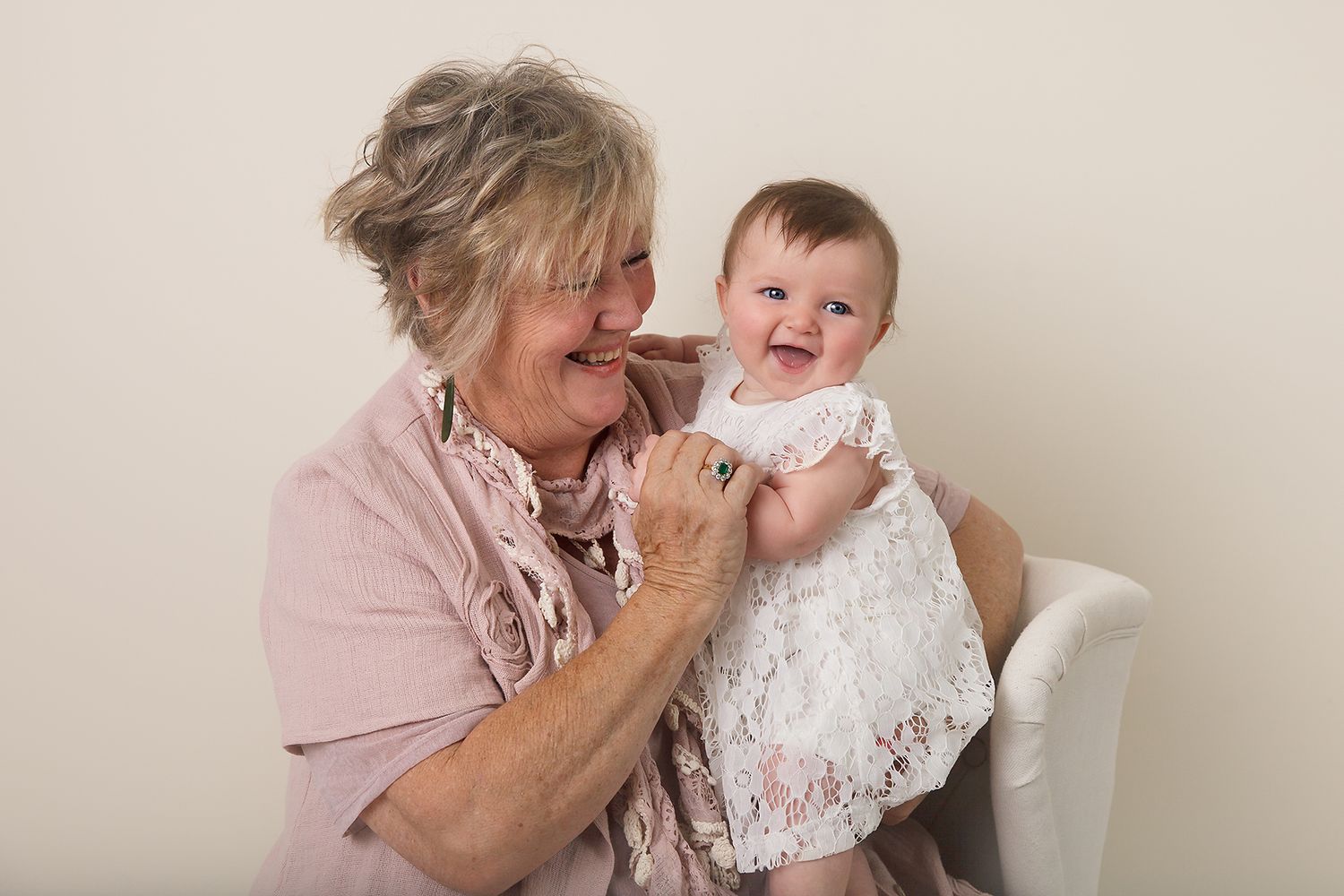 Sweet candid moment between older woman and baby in white lace dress.