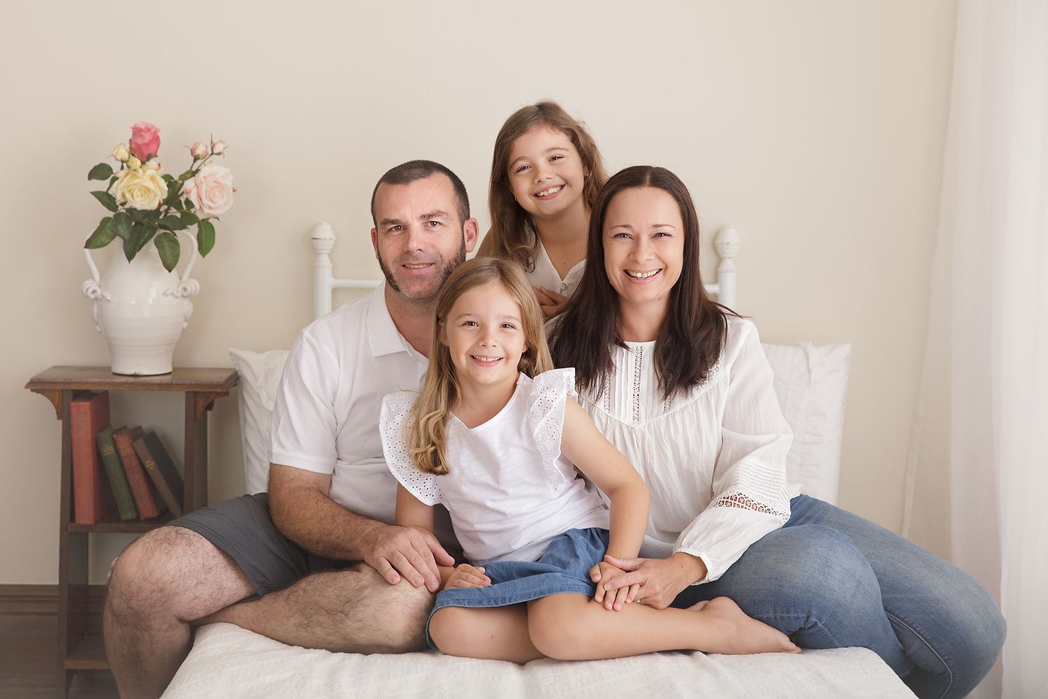 Casual family portrait on cream couch with white and neutral clothing.