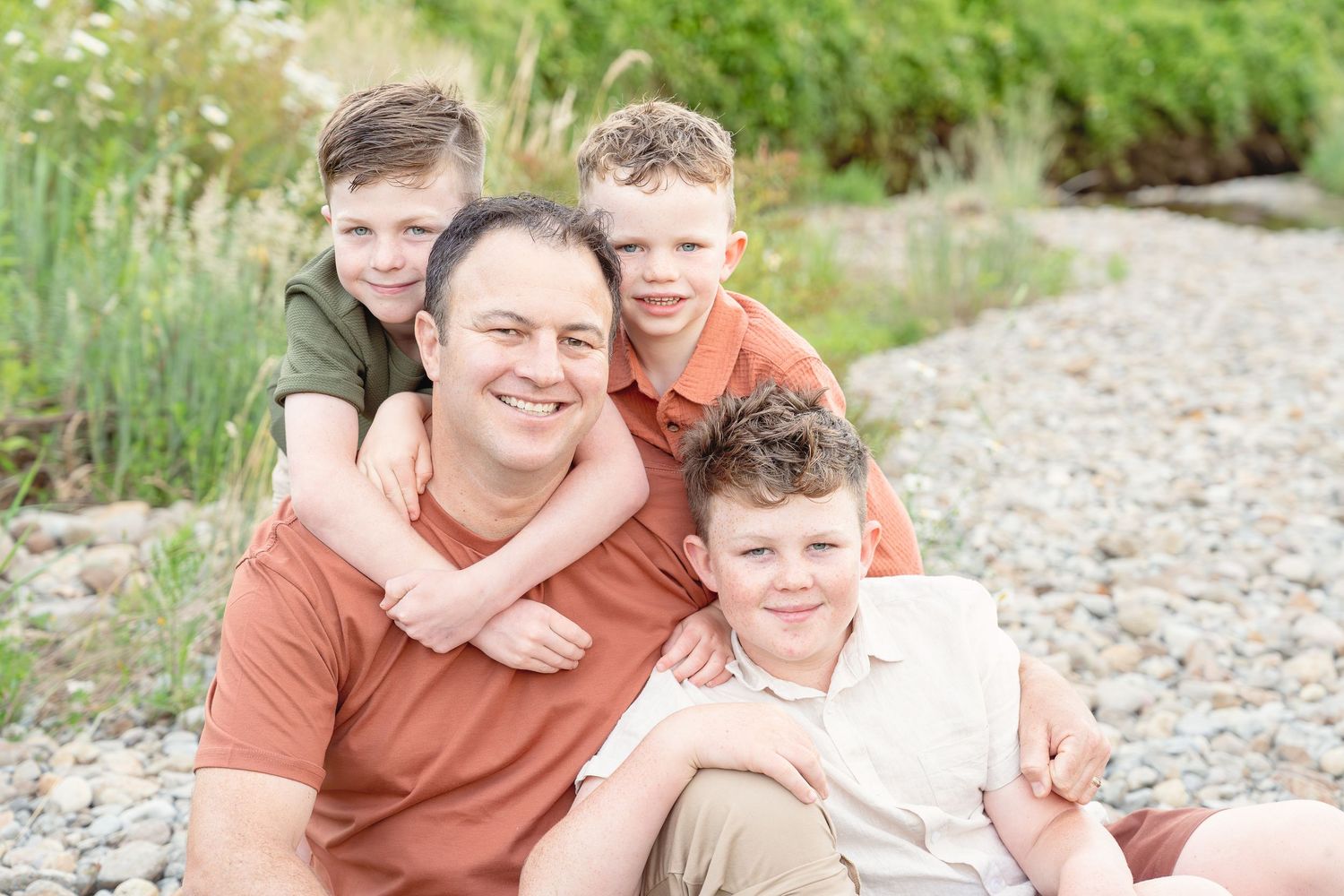 A group shares joyful moments together while sitting outdoors on a rocky beach area.