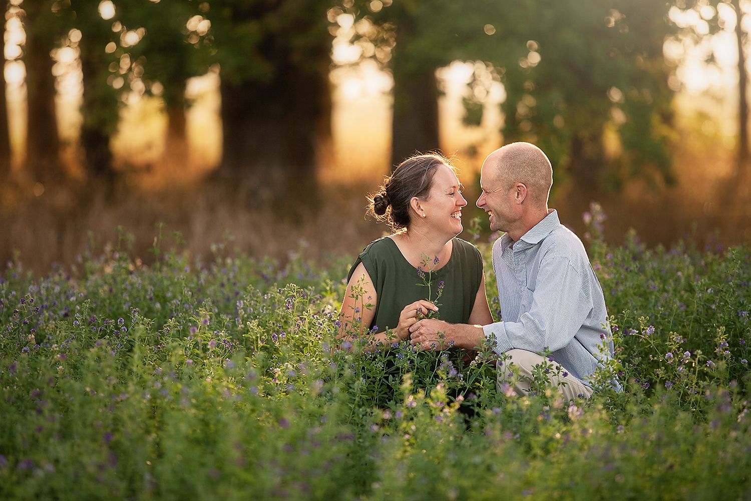 Couple shares intimate moments in a wildflower meadow at golden hour during outdoor photo session.