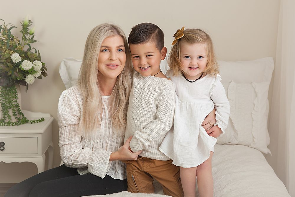 Casual family portrait with light background and floral arrangement.