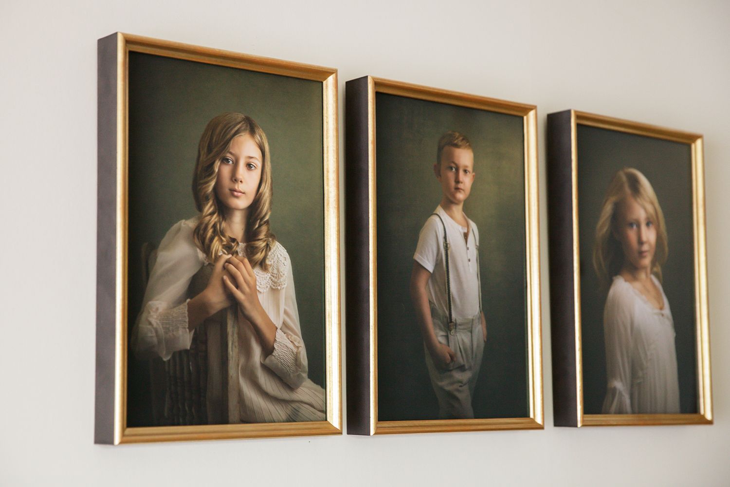 Gallery wall displaying series of framed fine art portraits in muted tones.