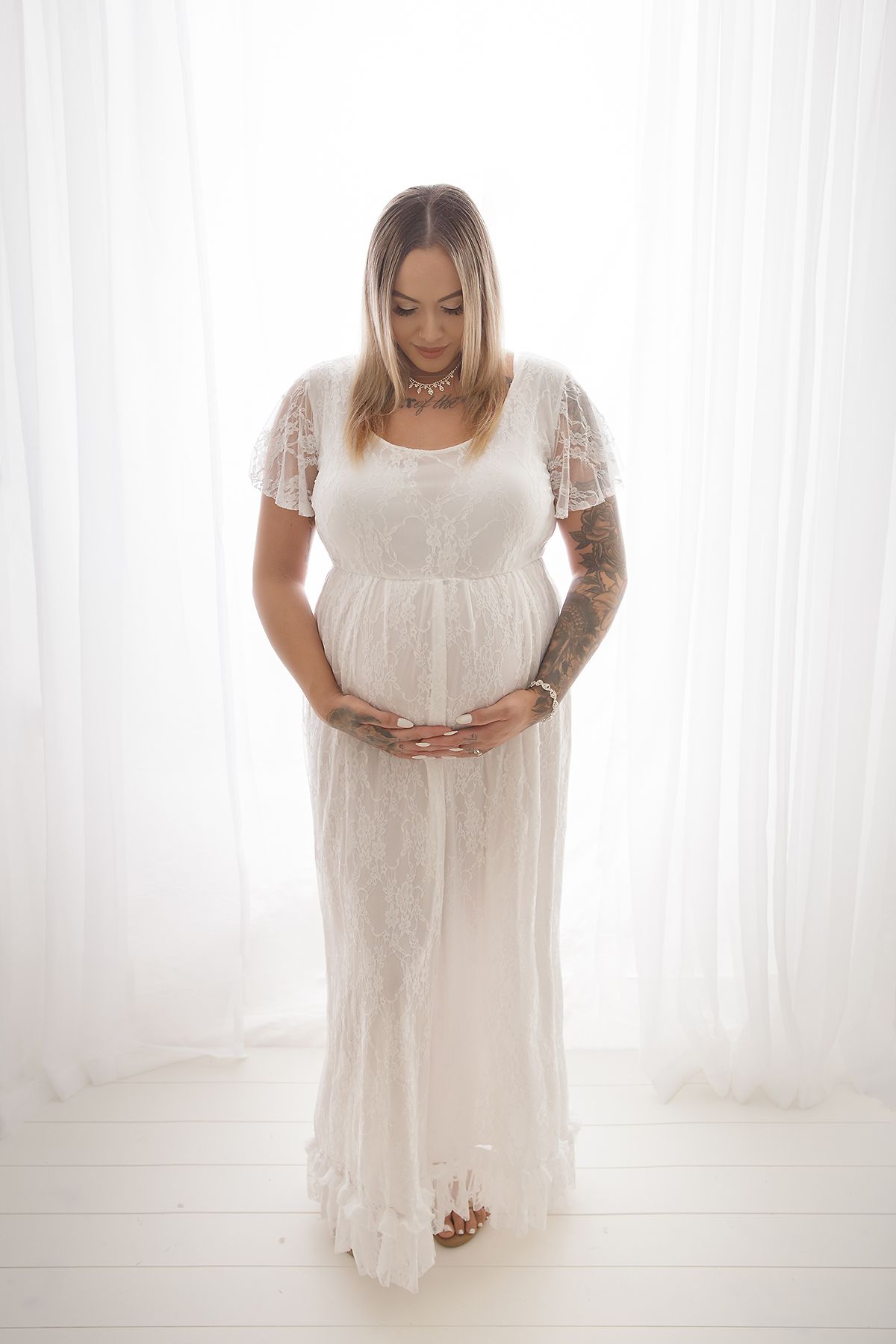 Minimalist maternity portraits showing woman in flowing white dress.