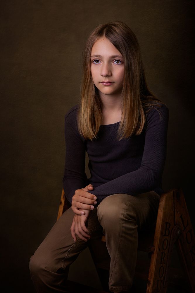 Dark toned studio portrait with dramatic lighting and muted earth colors.