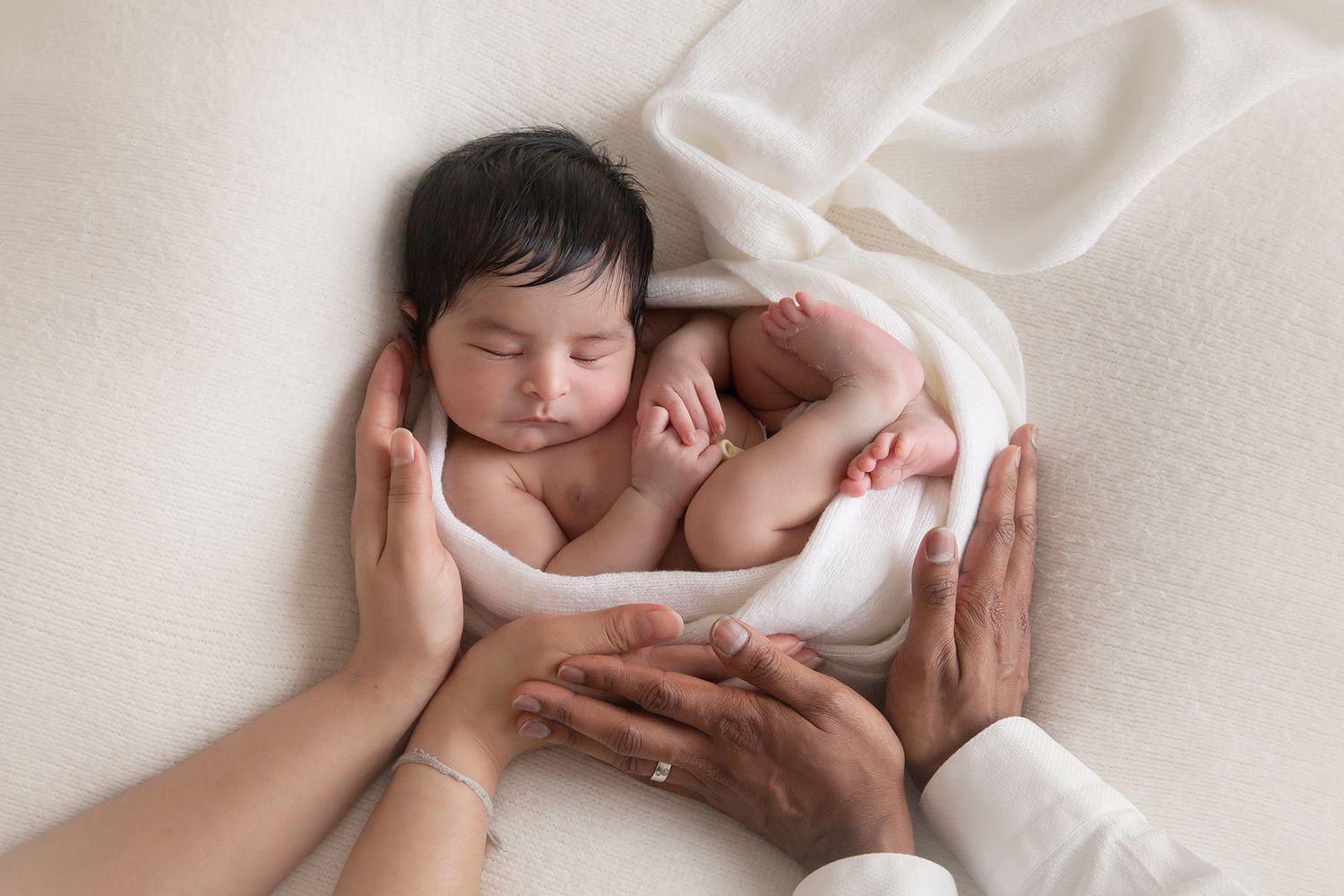 Peaceful sleeping newborn swaddled in white blanket.
