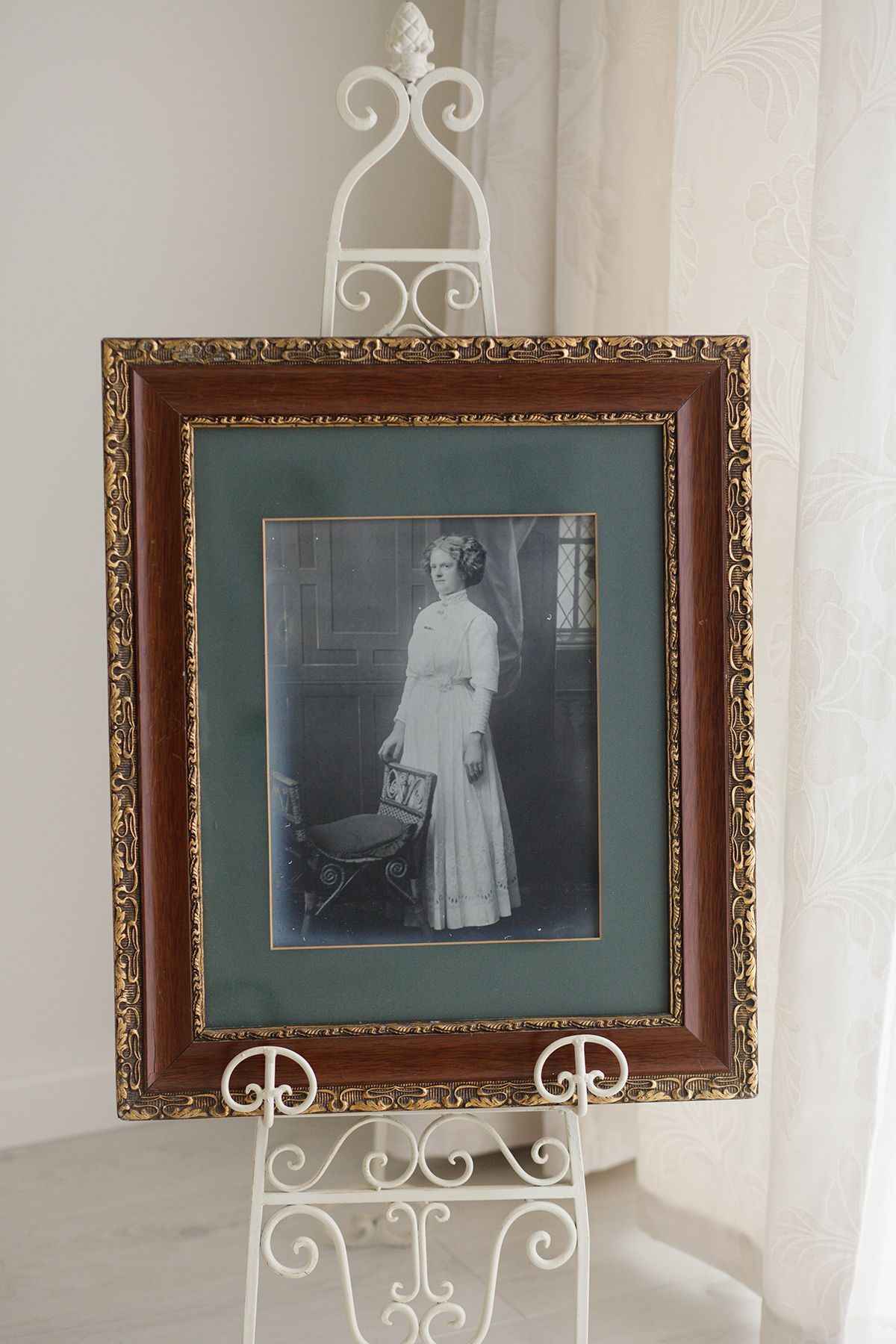 Vintage black and white photographs displayed in ornate gold frames on white decorative easels.