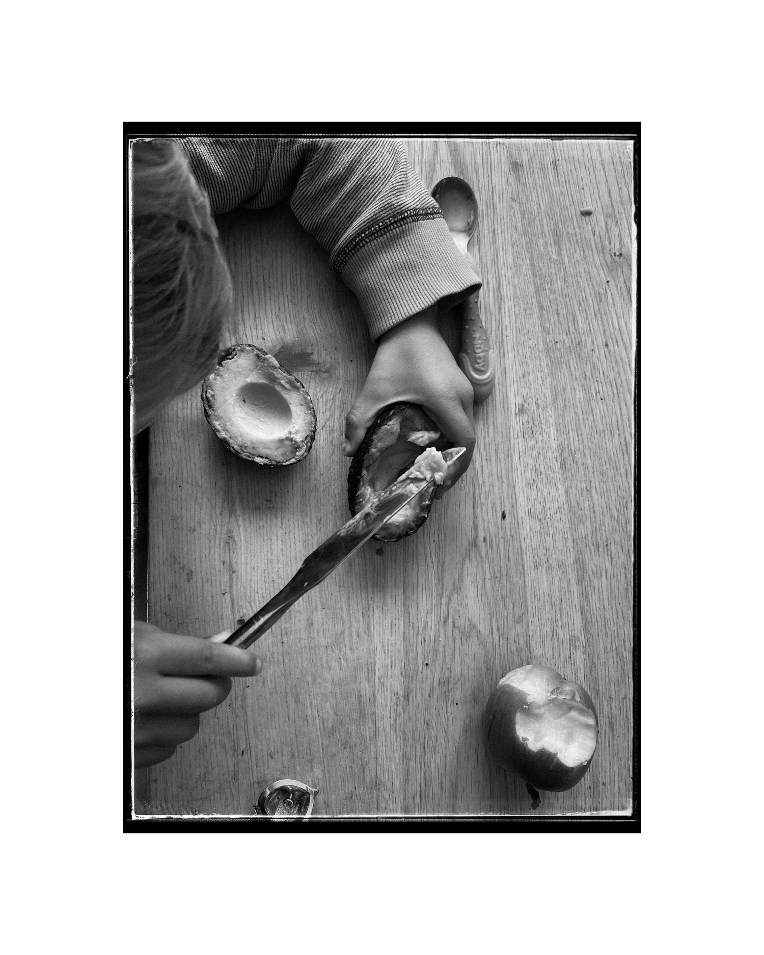 Overhead view of hands cracking open an egg on a wooden surface.
