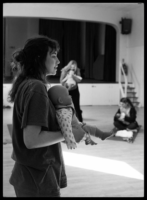 Dance students practicing expressive movements in a bright studio space captured in black and white photography.