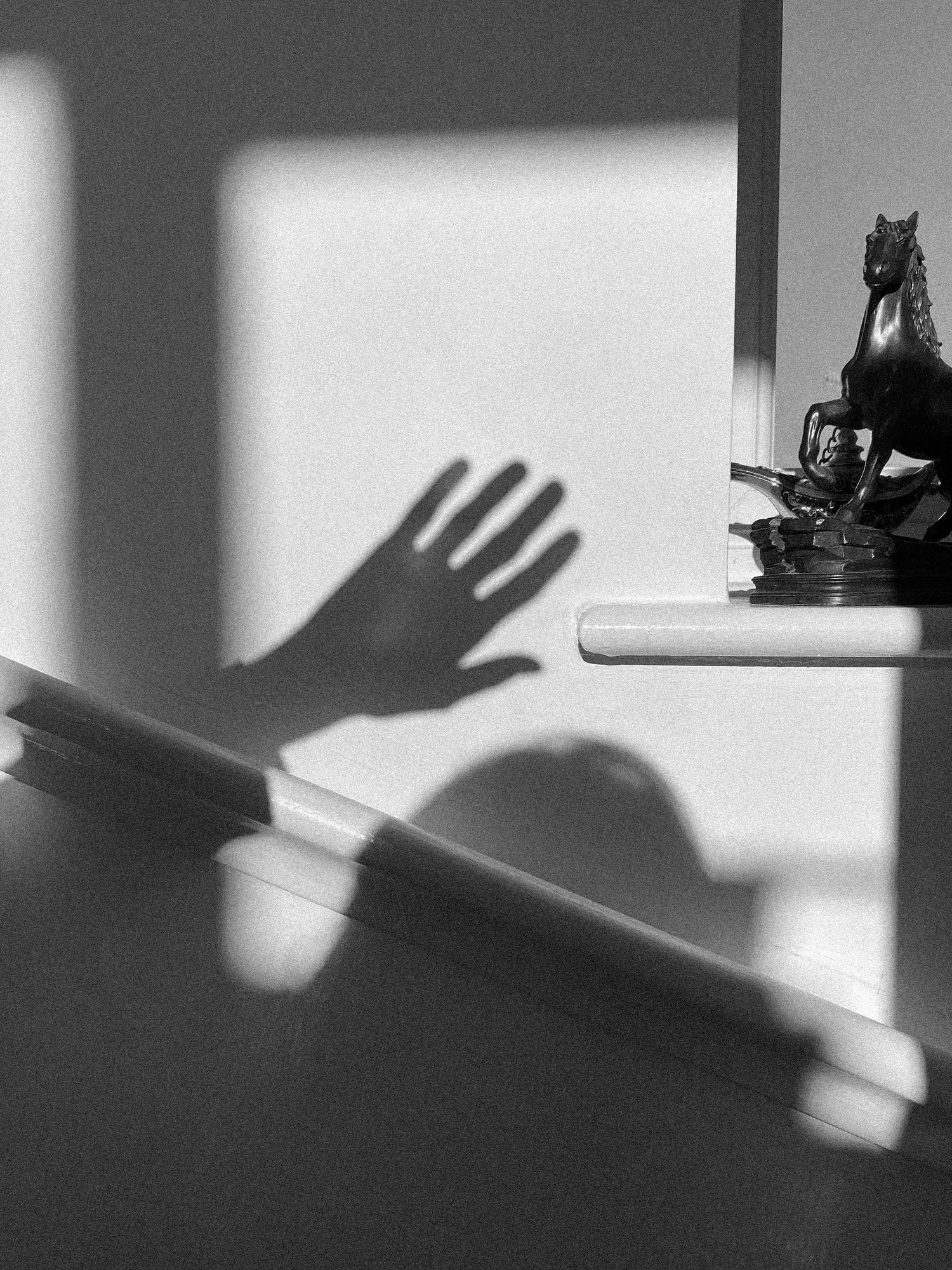 Dramatic shadows of hands cast on a white wall create a artistic sequence.