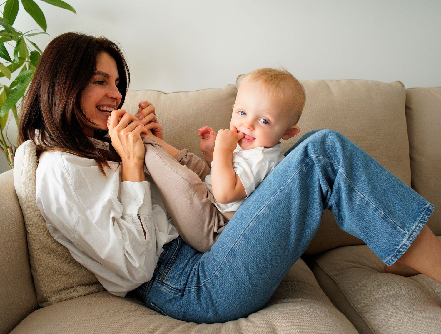 Relaxed lifestyle moments captured on a couch with a baby and casual denim attire.