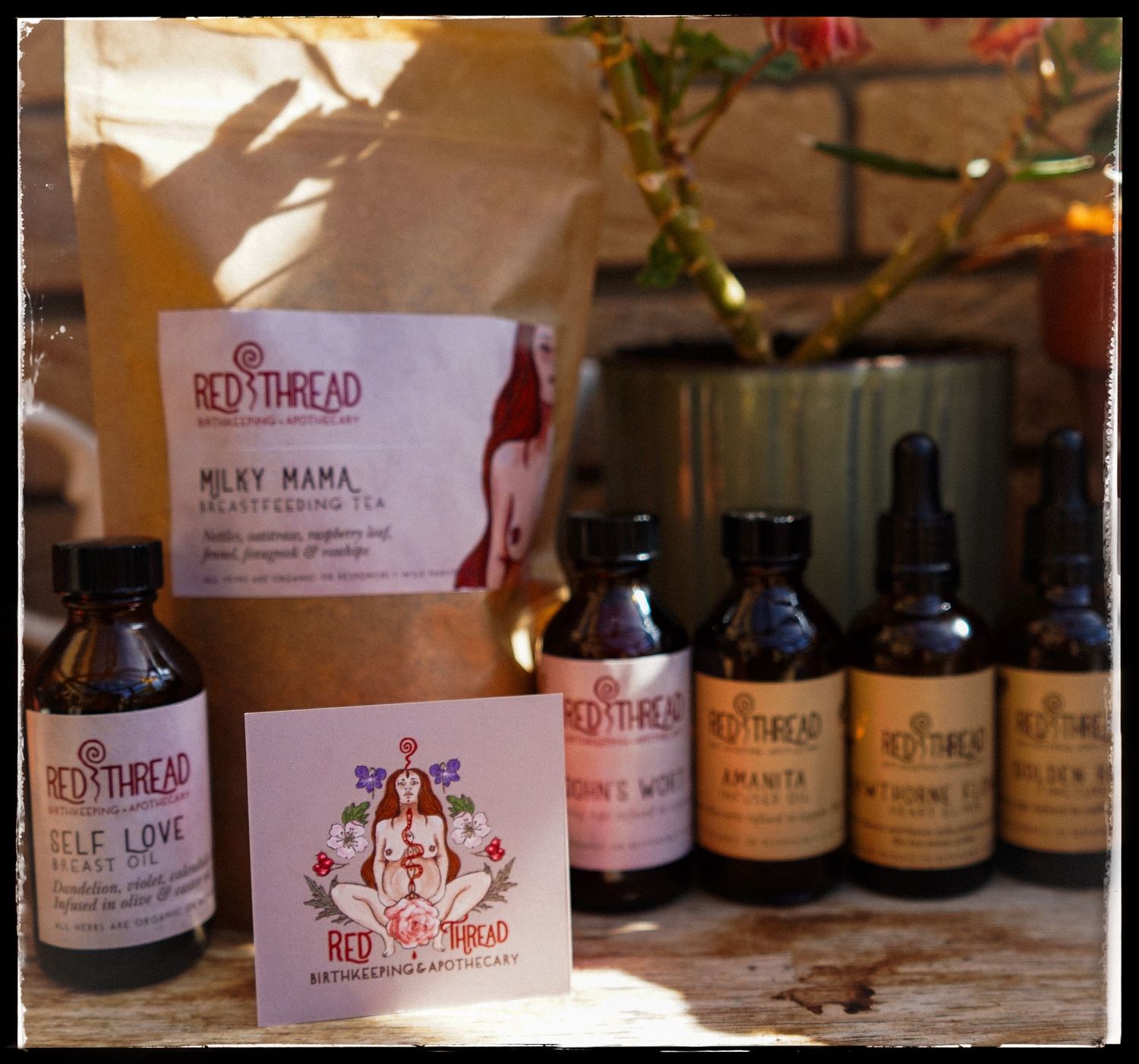 Several brown bottles and a paper package of wellness products displayed on a wooden surface with a business card.