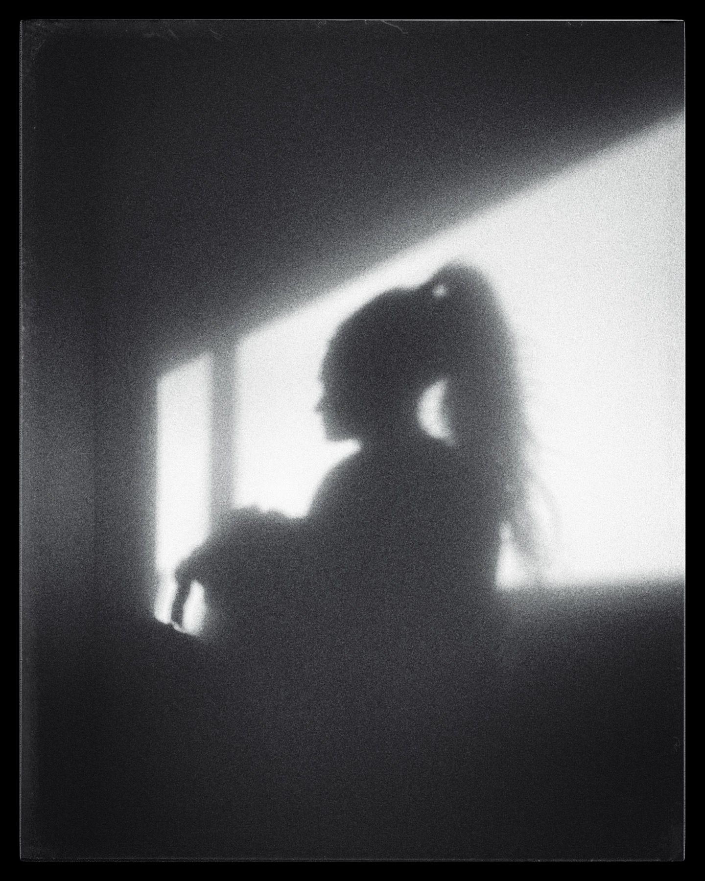 Artistic silhouette photograph showing a shadowy figure against a bright window.