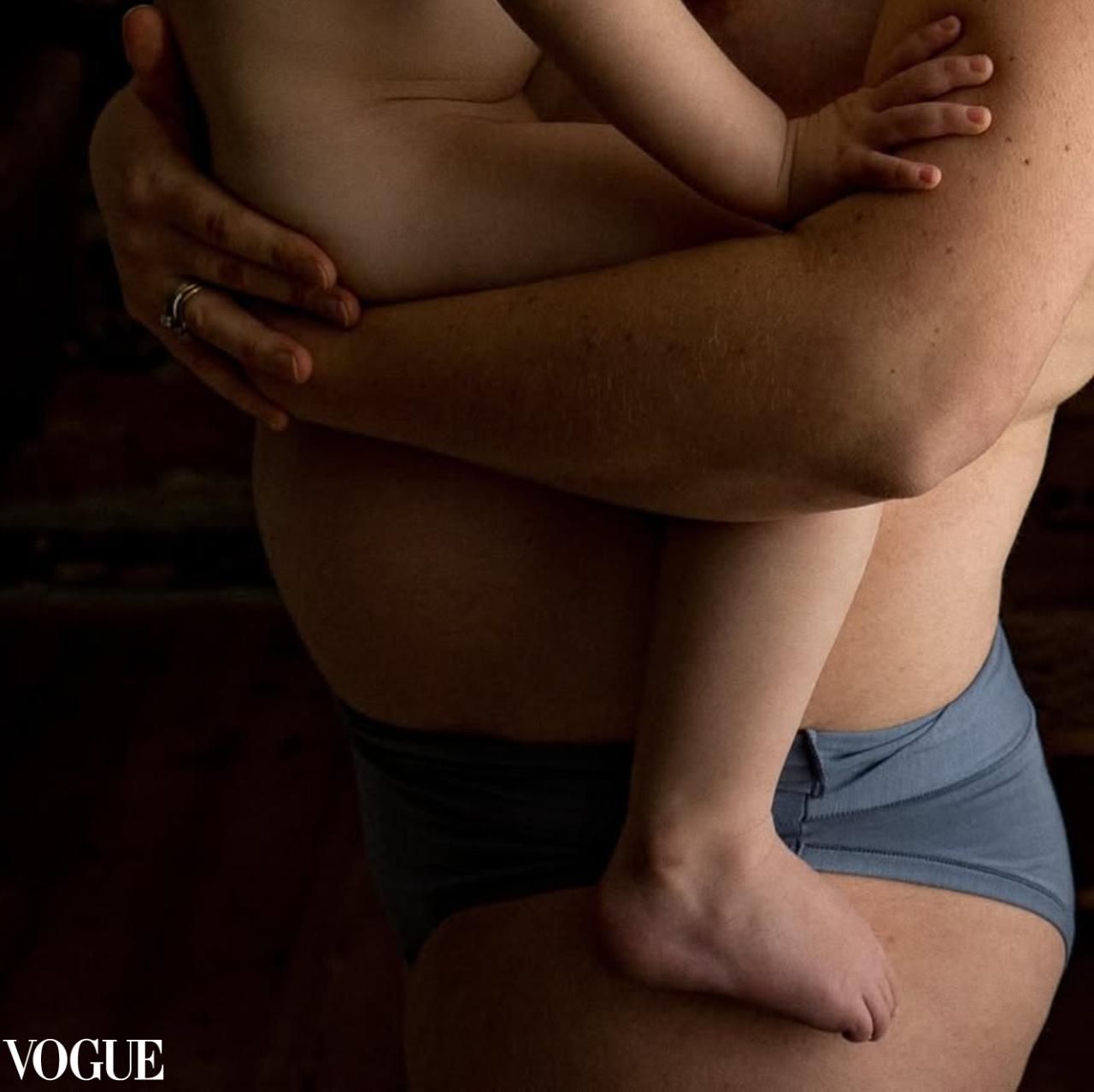 Artistic close-up photograph of bare skin and tiny hands against blue fabric.
