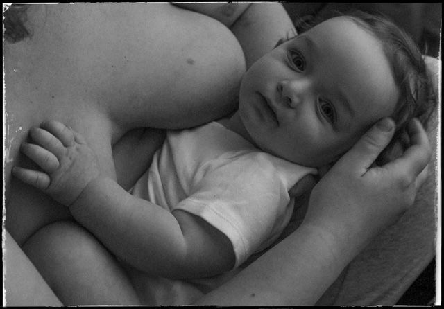 Seven black and white close-up baby photos arranged in a horizontal filmstrip sequence showing various poses and expressions.