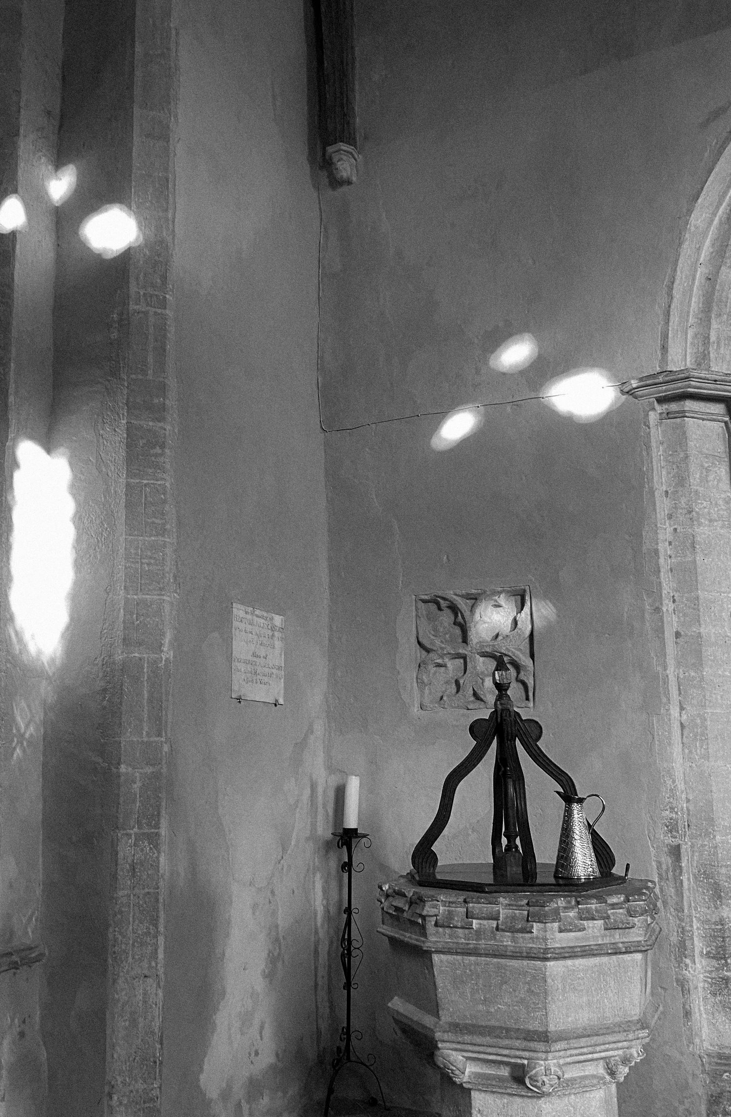 Black and white interior photograph of a church showing a chandelier and arched architectural details.
