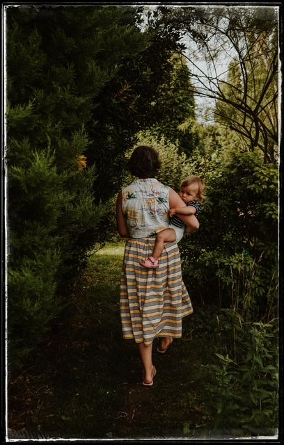 A peaceful garden path scene with a striped summer dress against lush greenery on a sunny afternoon.