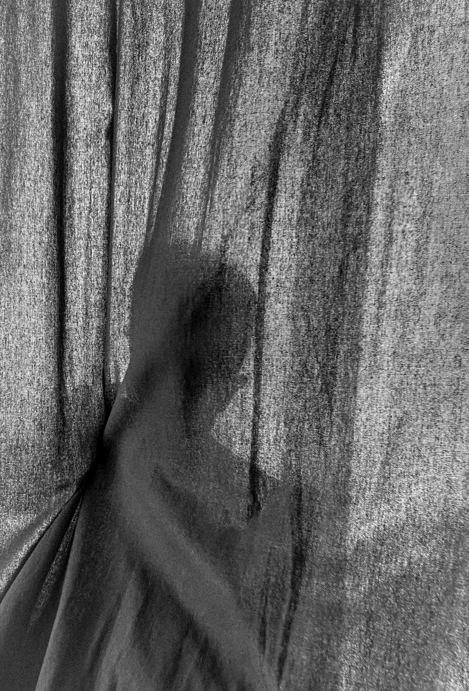 Silhouetted figure behind textured fabric creating mysterious shadow effect.