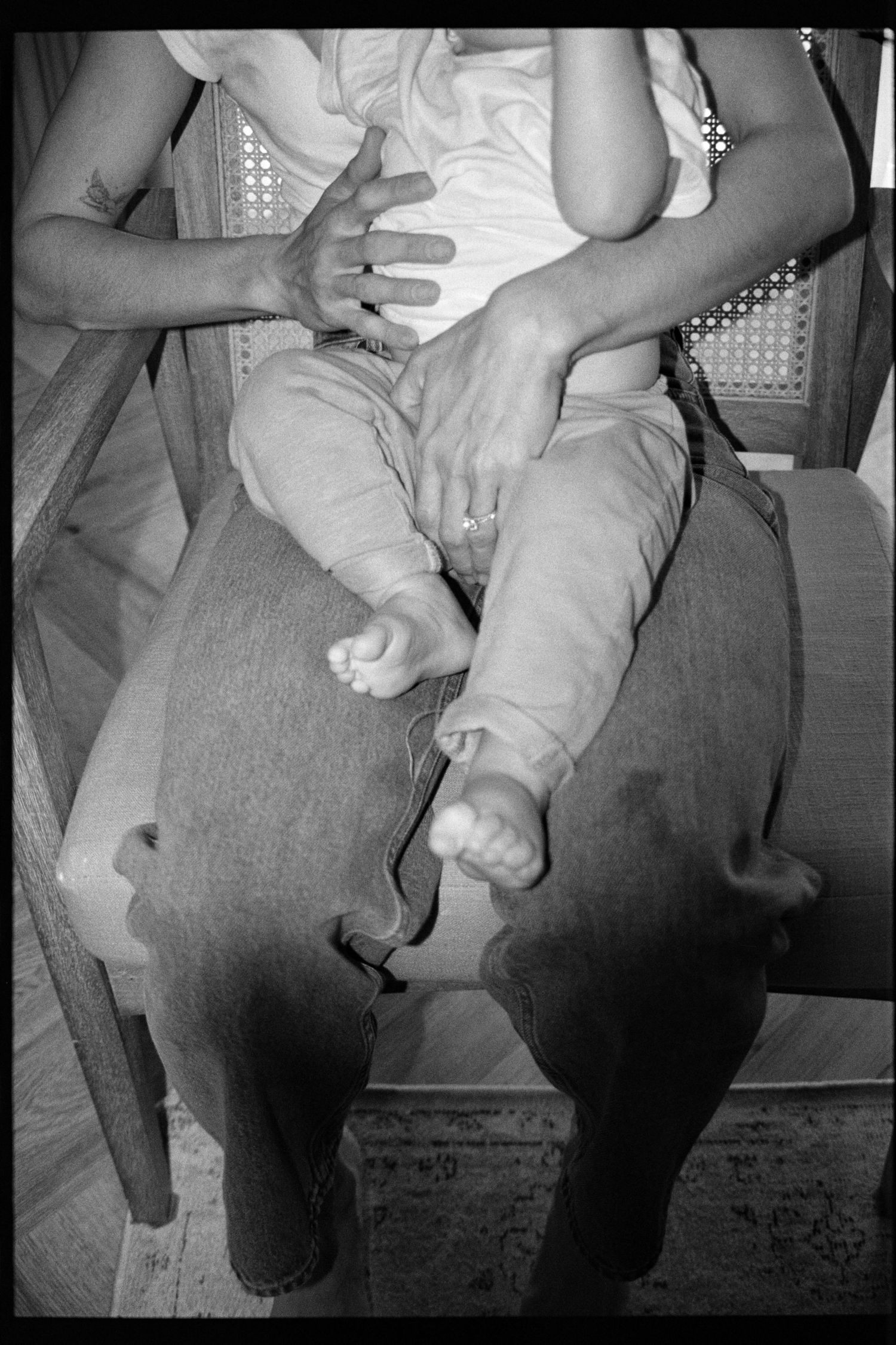 Black and white photo sequence showing a baby being held and supported while sitting on someone's lap.