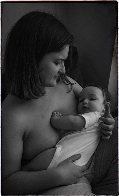 A black and white intimate portrait of tender bonding moment between parent and sleepy infant.