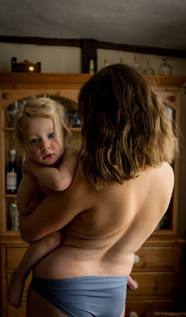 Intimate mother and child portrait in front of wooden cabinet showing tender maternal care.