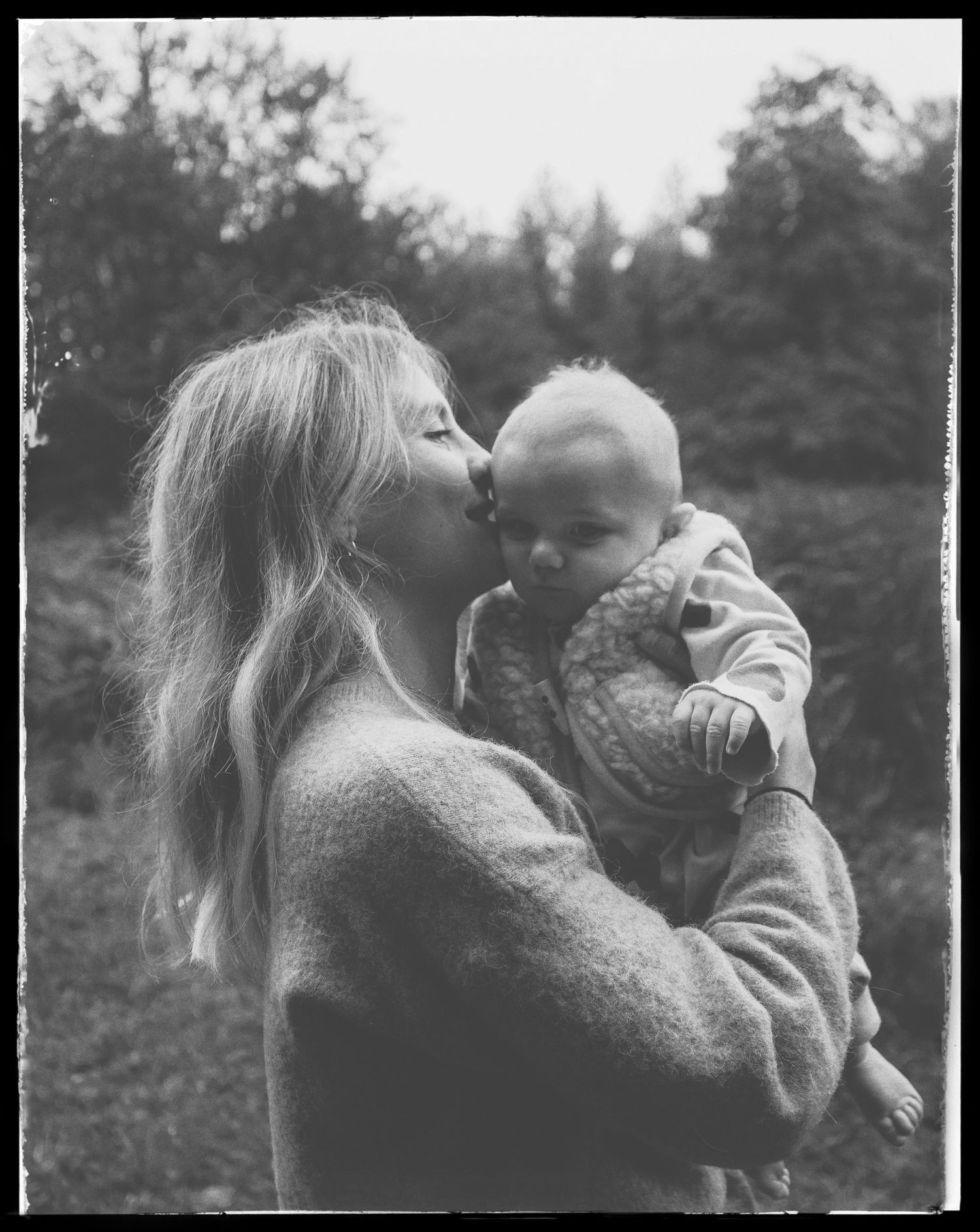 Intimate black and white outdoor portrait of tender moment between parent and baby.