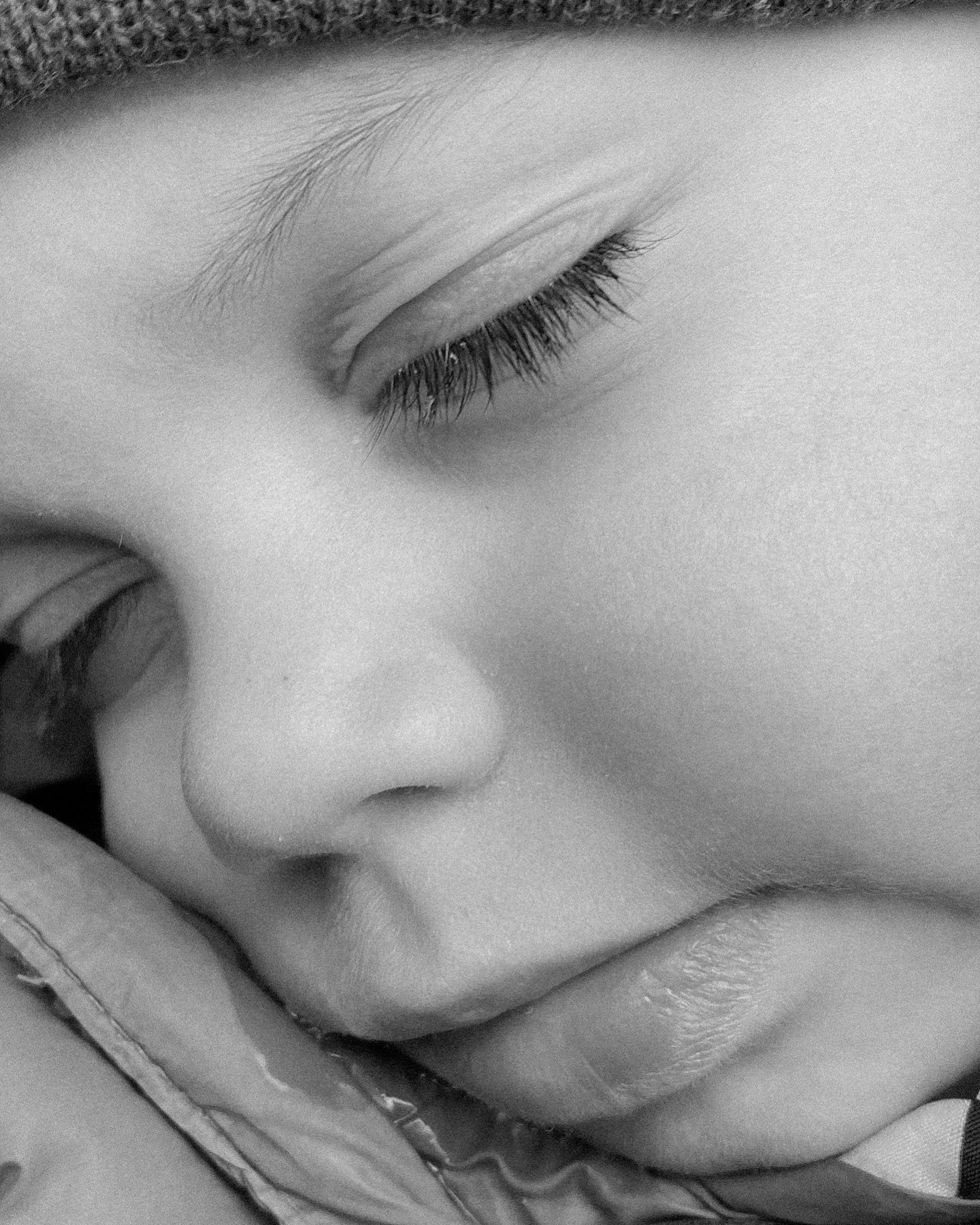 Close-up black and white photograph showing peaceful sleeping features in soft light.
