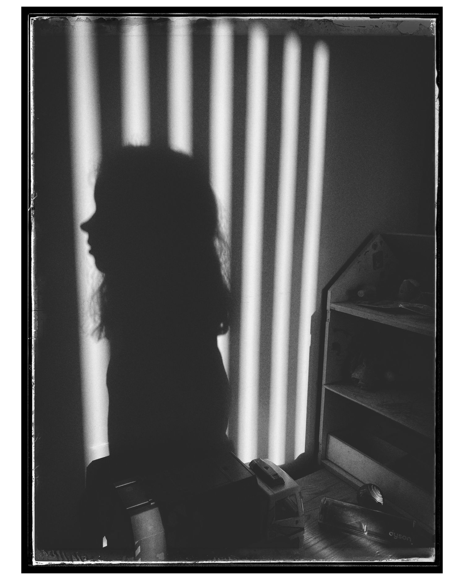 Dramatic silhouette against vertical light stripes creating a moody noir atmosphere.
