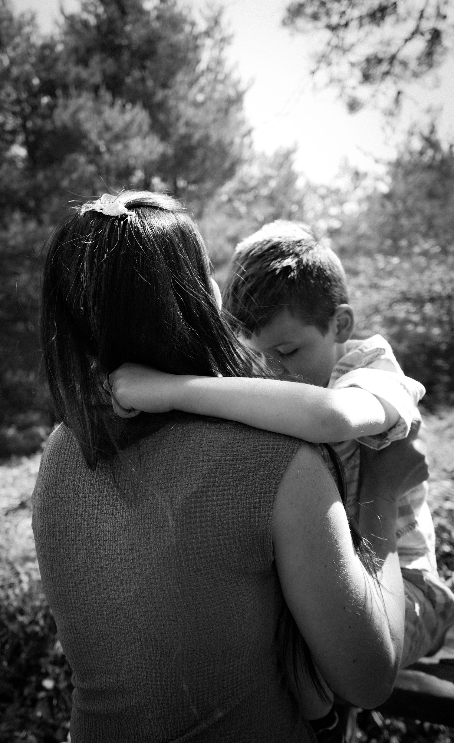 A tender black and white moment captured of a parent holding their child in a natural outdoor setting.