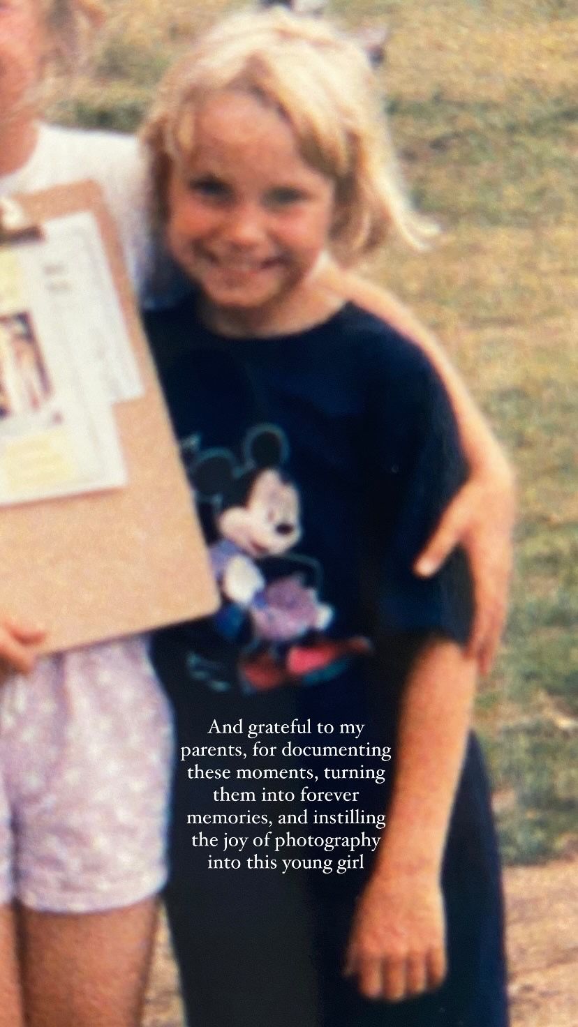 A vintage photograph showing someone wearing a Mickey Mouse t-shirt while holding papers outdoors.