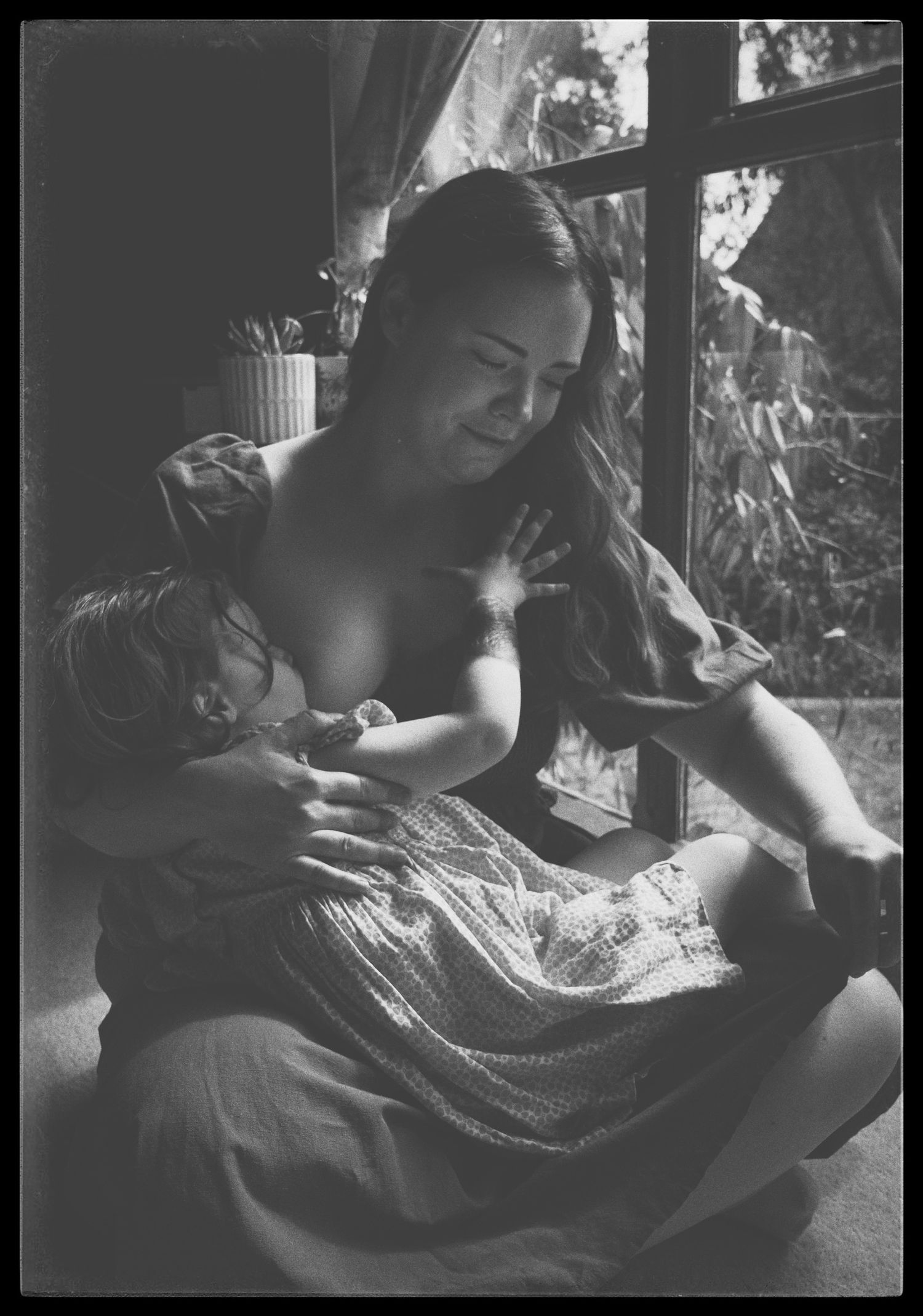 A tender moment captured in moody black and white lighting showing gentle interaction with soft textiles.