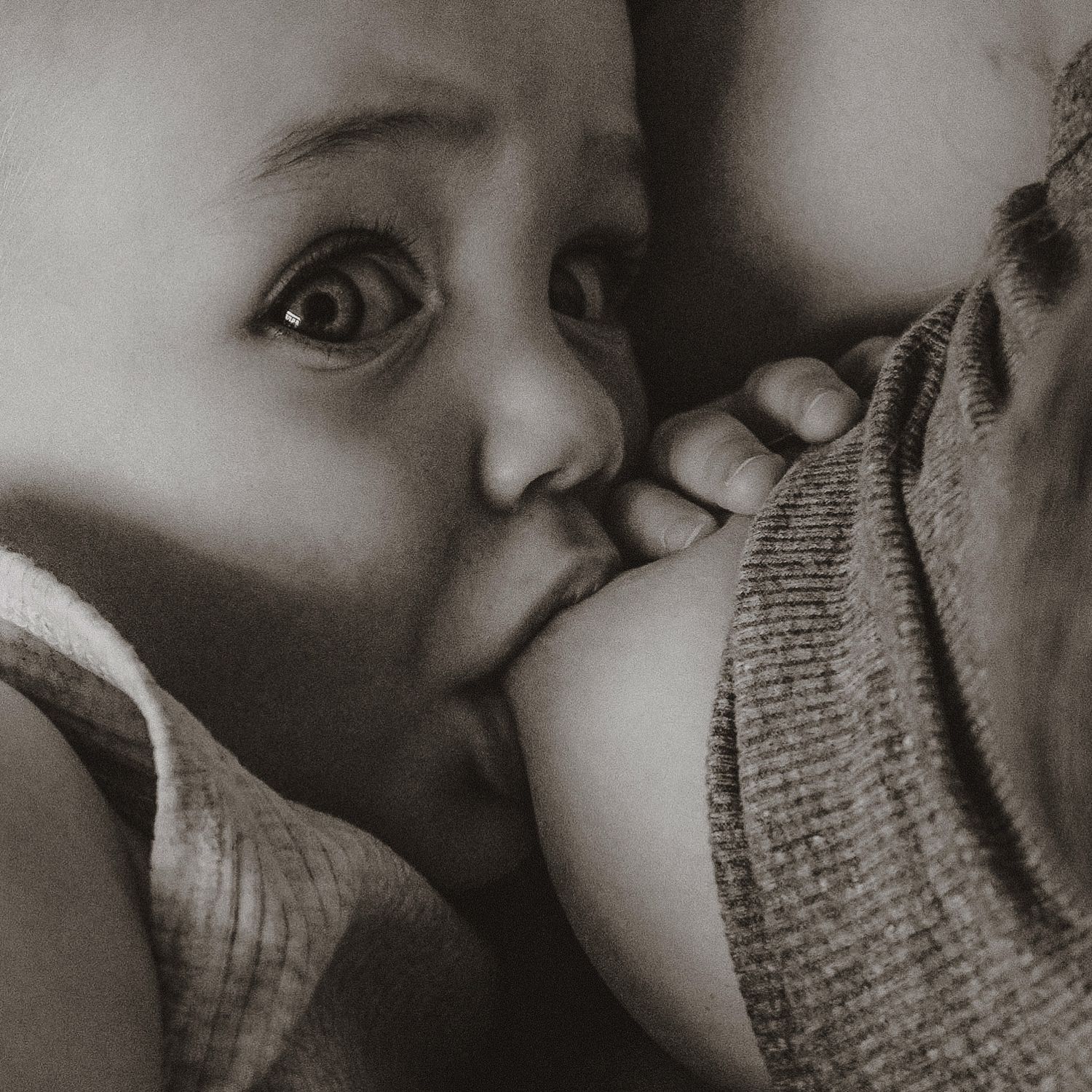 Close-up black and white photo of a baby during breastfeeding.