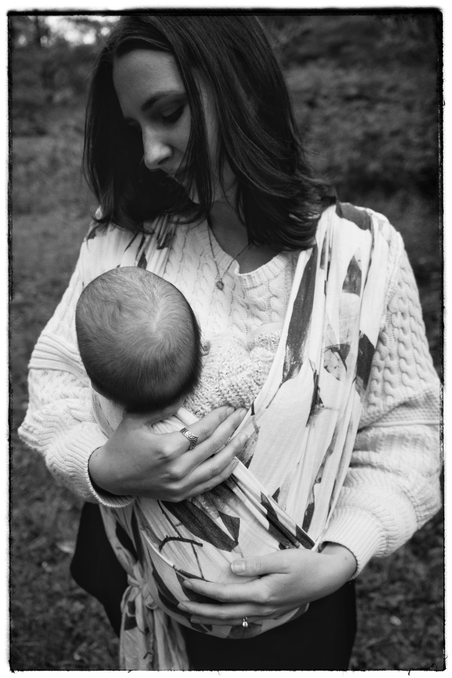 An intimate black and white photograph shows a mother in white lace cradling her baby against her chest.