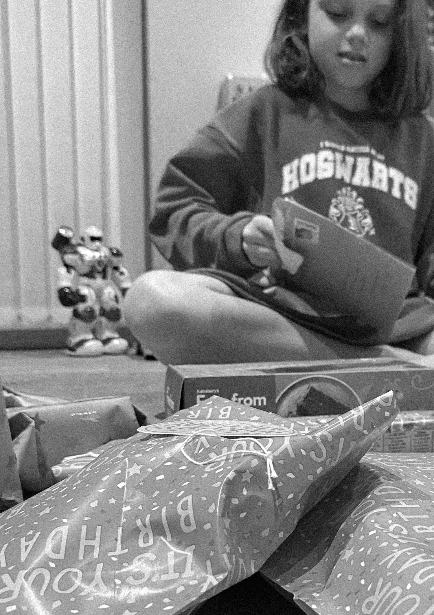 Reading materials and packages scattered around with a toy figure visible in black and white.