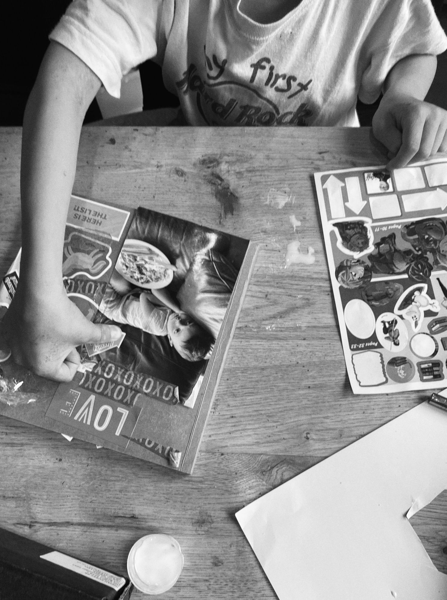 Overhead view of books and papers scattered on a wooden table surface.