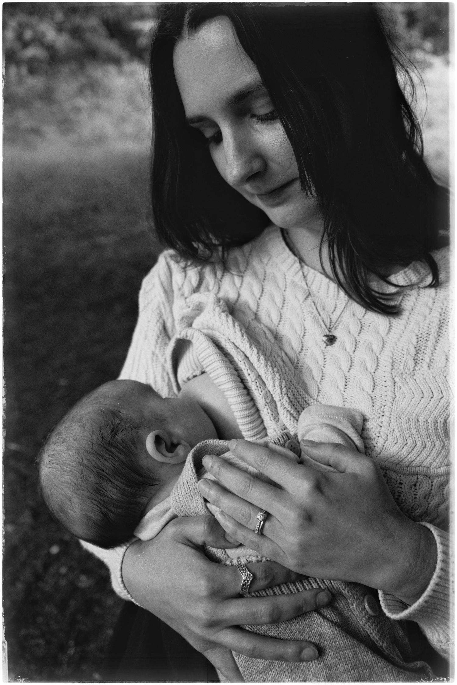 Black and white series showing a tender moment between a parent in a knit sweater cradling and looking down at a baby.