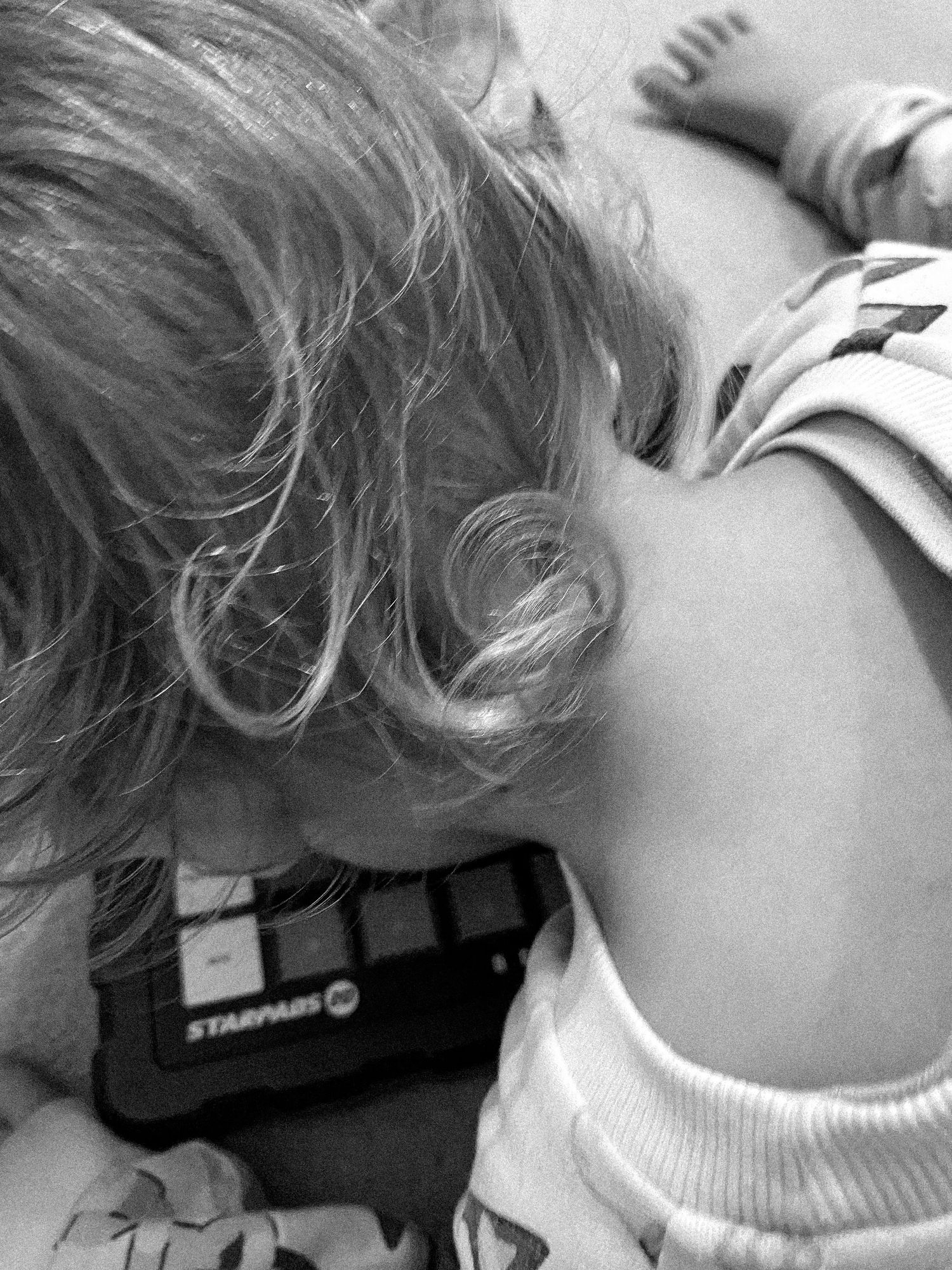 Close-up black and white photo of child playing with electronic device.