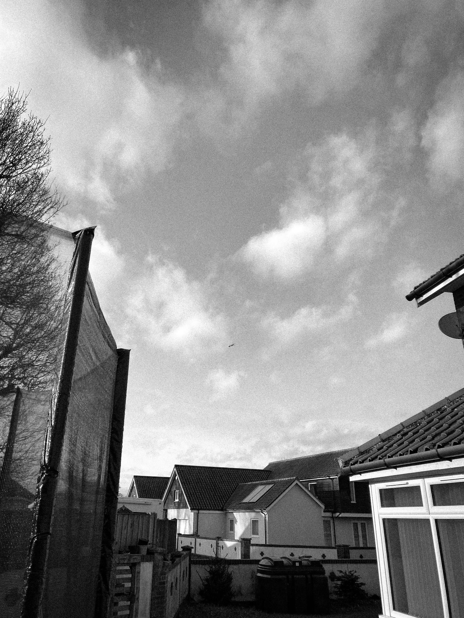Black and white architectural photo of suburban houses against a cloudy sky.