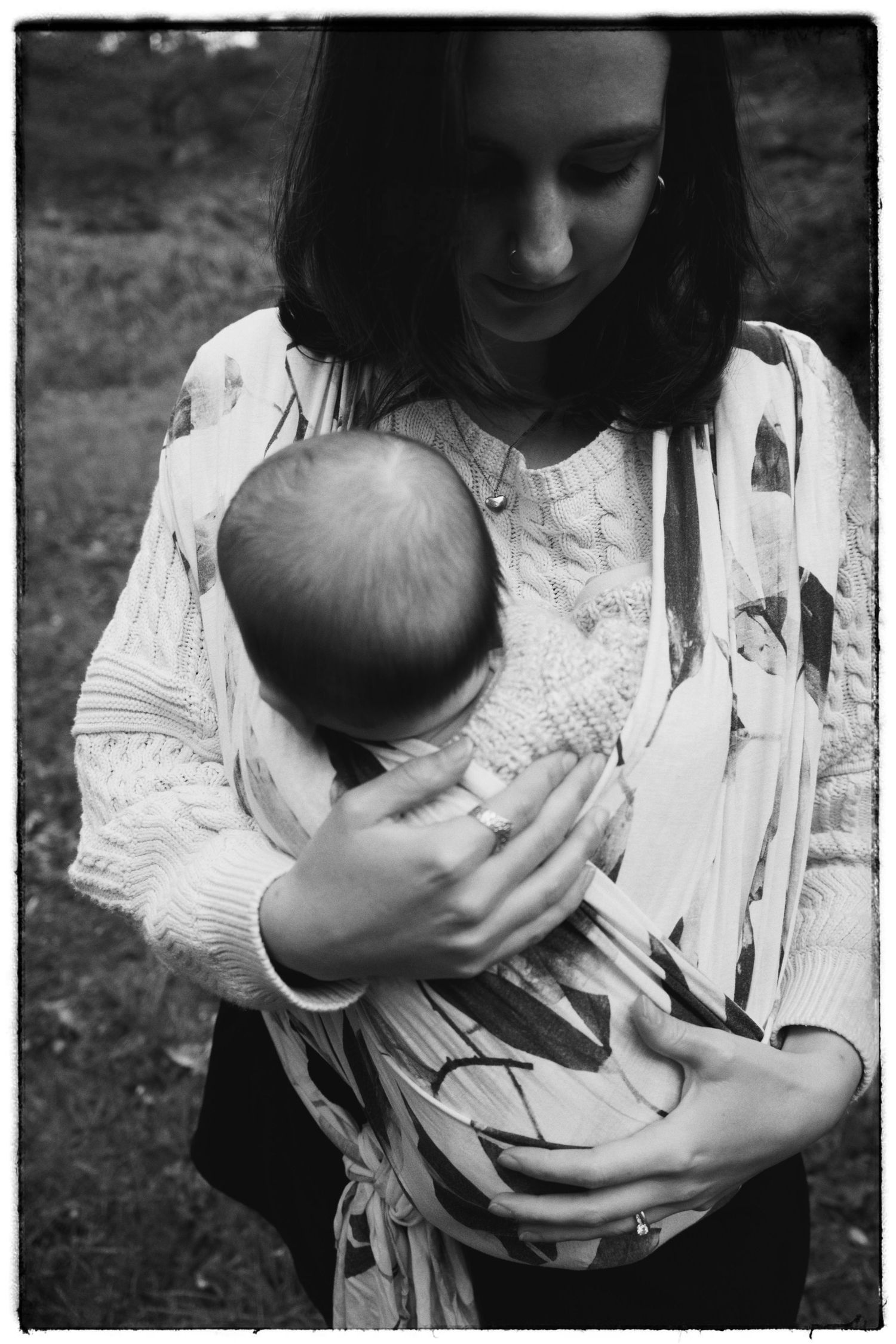 A tender moment captured in black and white as a baby is held close in soft light.