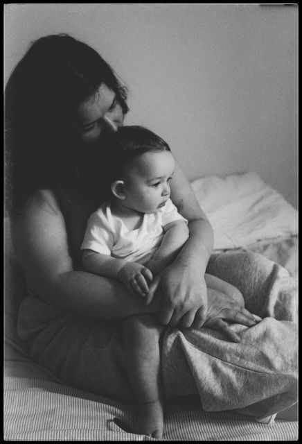 A sleeping infant snuggles against pillows in a peaceful black and white photograph.