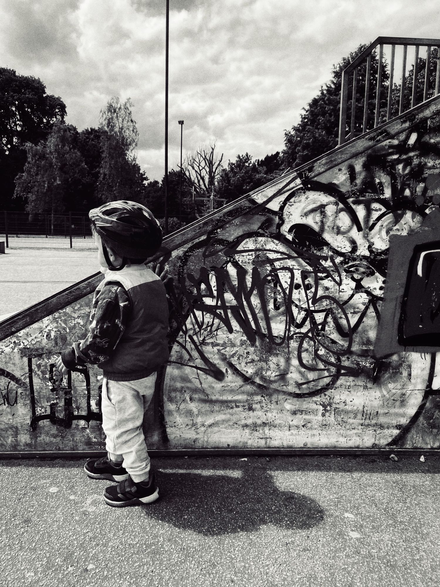 Black and white shot of skateboarding moves against a graffiti wall.