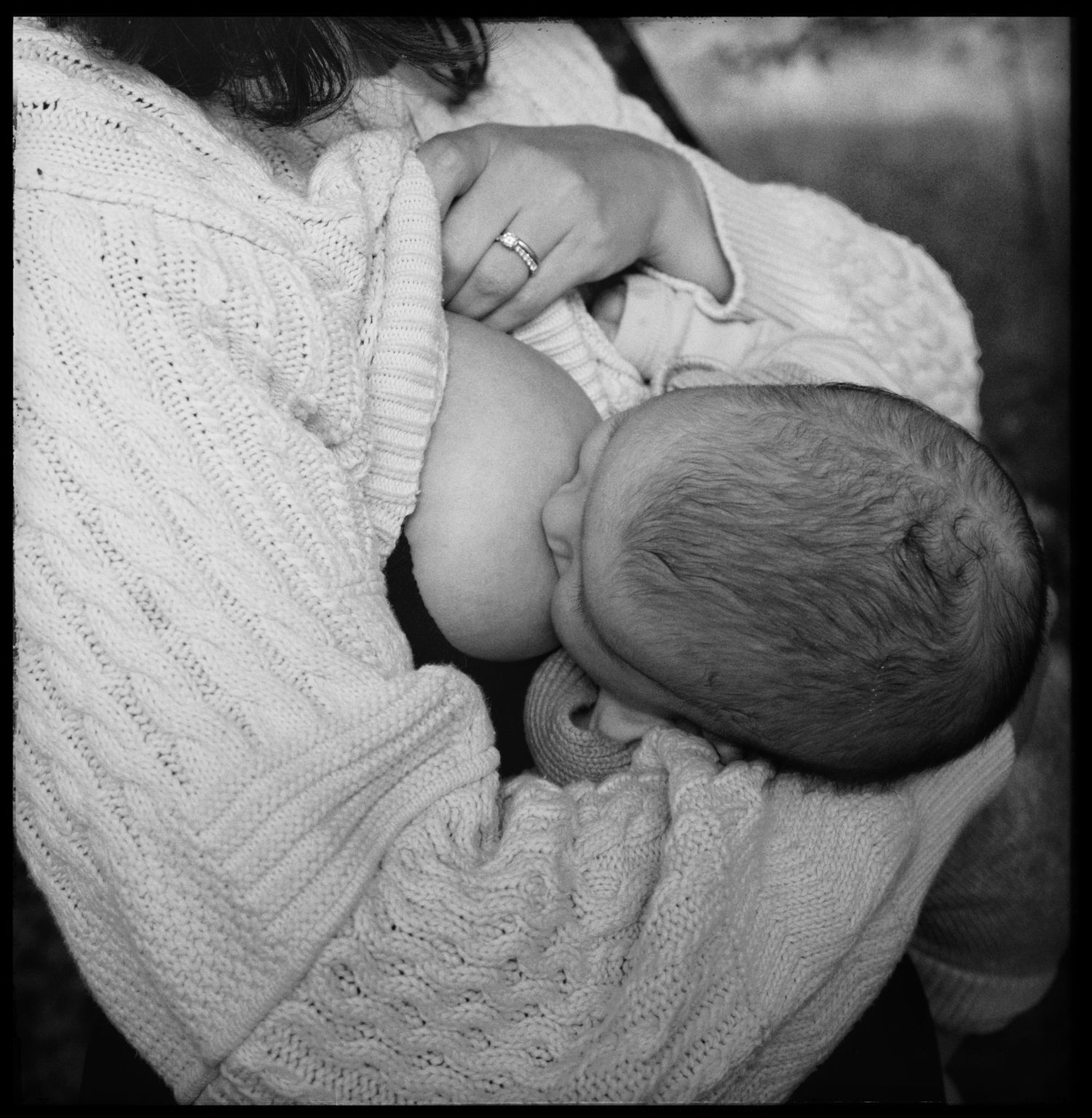 Close-up black and white image showing gentle embrace in cable knit sweater.