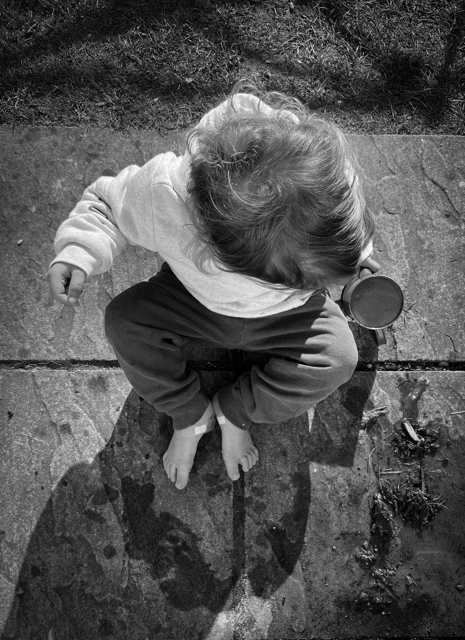 Aerial view of someone sitting on concrete ground viewed from directly above.