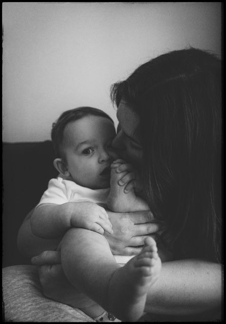 A sequence of black and white photos showing intimate moments between a baby and parent lying together.
