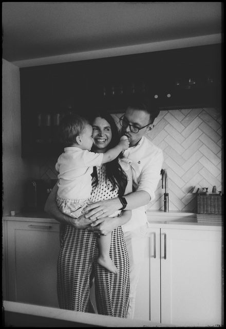 Black and white film sequence showing a candid interaction between two people in a kitchen interior.