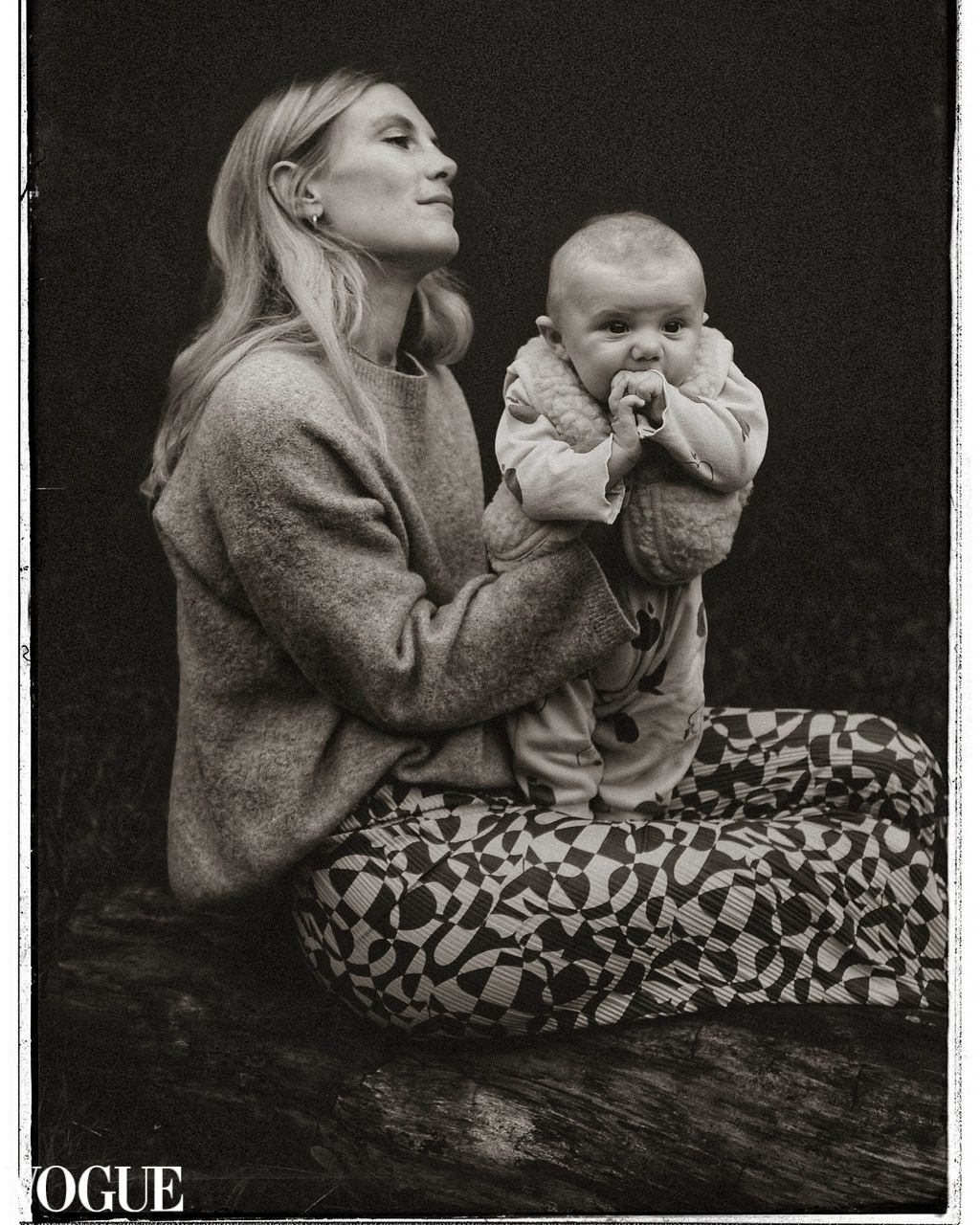 Black and white portrait of parent and baby in cozy sweaters sitting together.