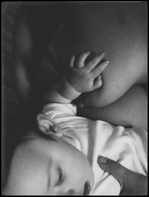 A tender black and white close-up photograph of a sleeping baby wearing white clothing.